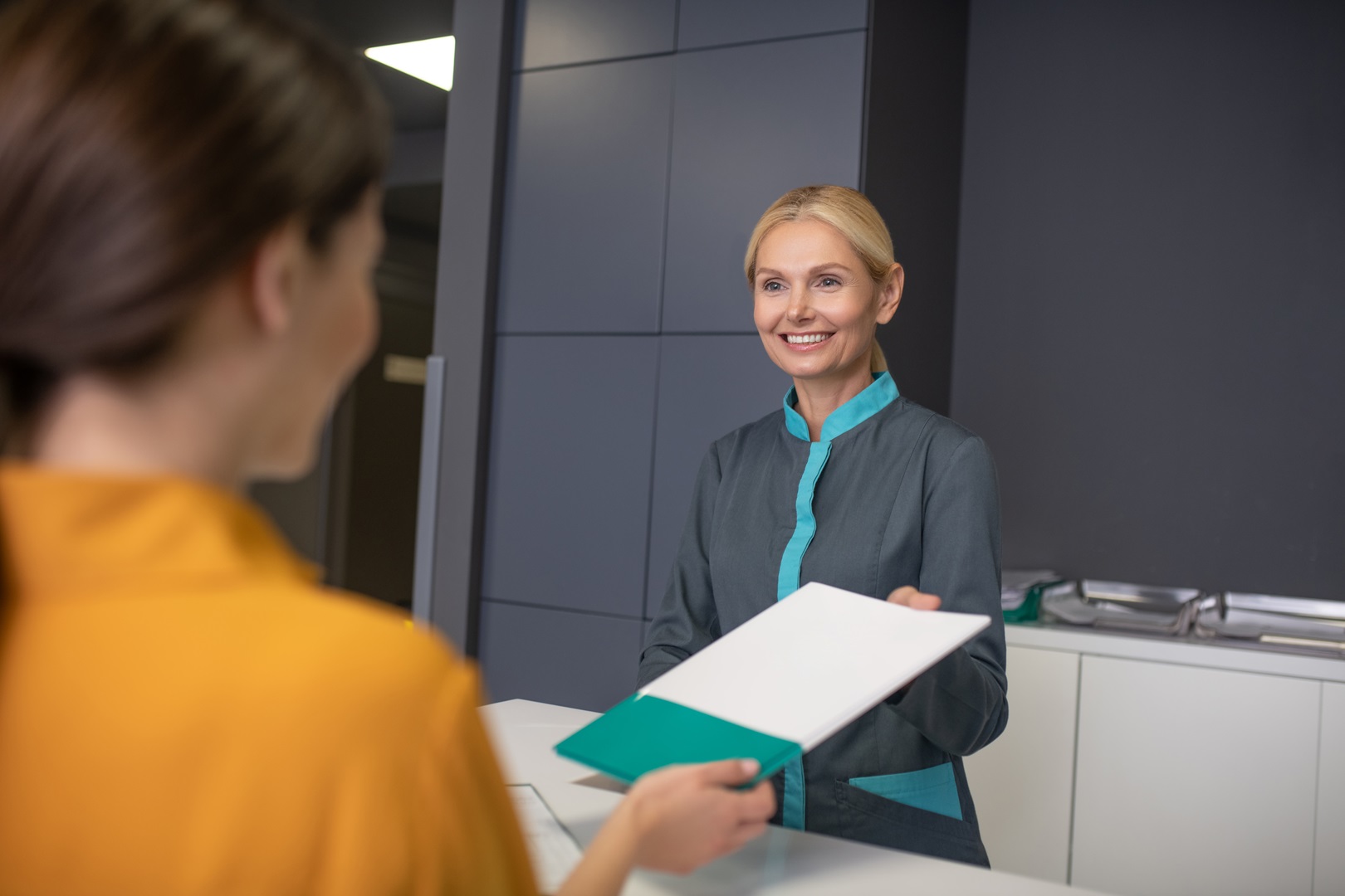 Receptionist helping with patient documentation by greeting patients